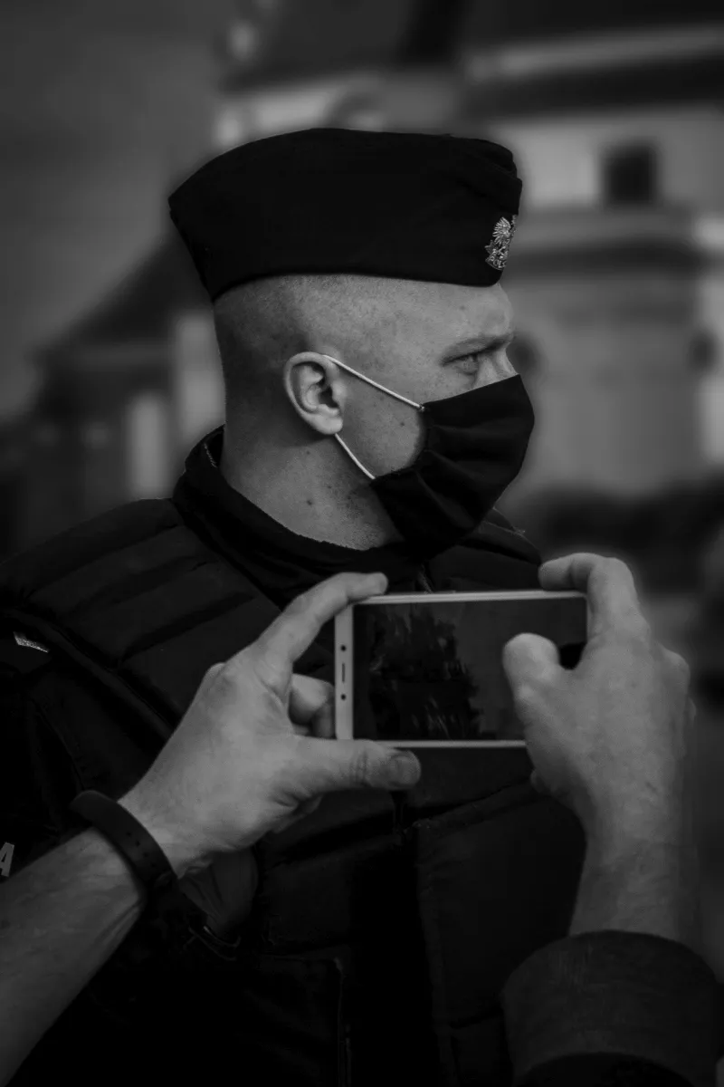 Masked police officer being photographed with a smartphone